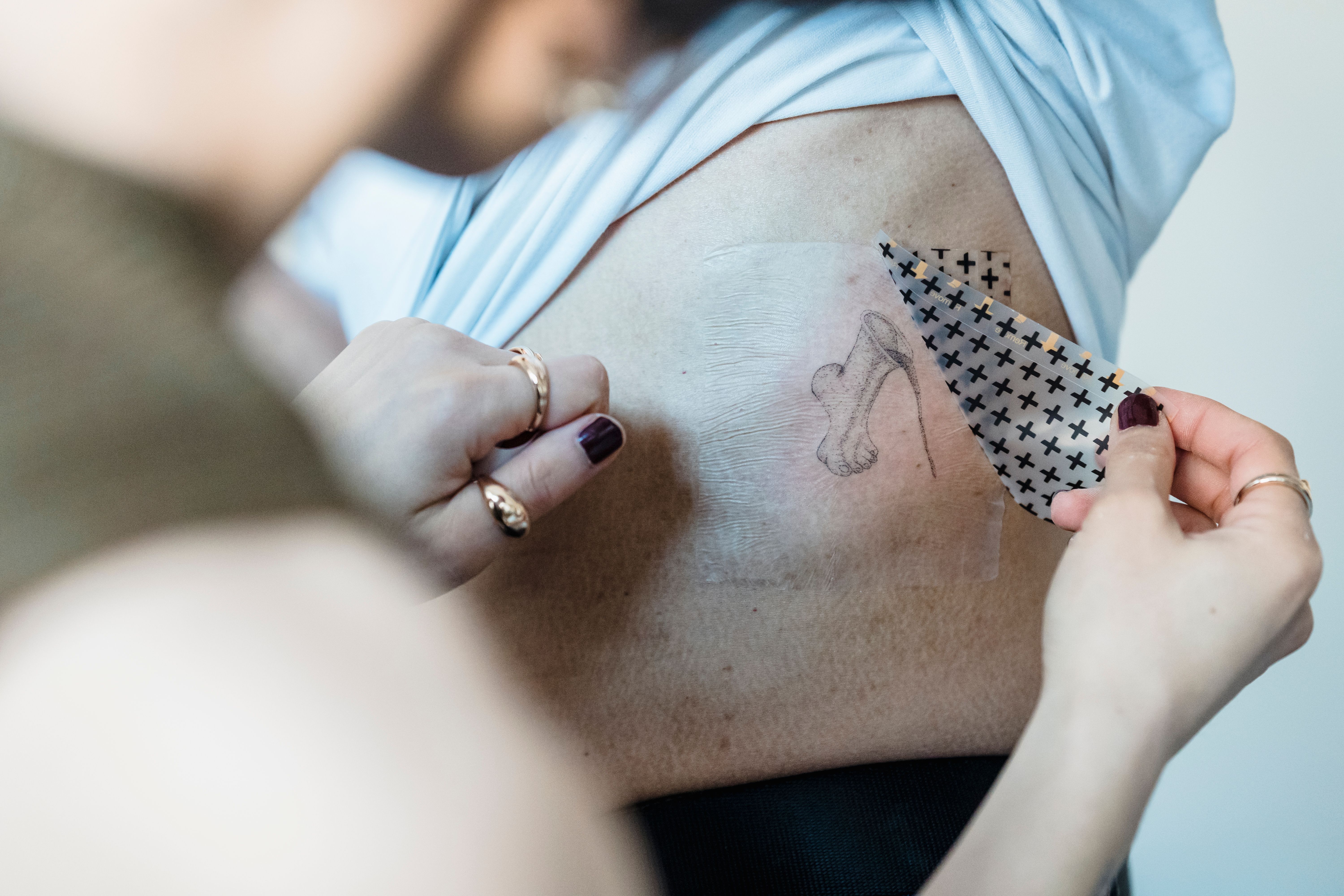 Remoção da segunda pele sob água morna para não machucar a tatuagem